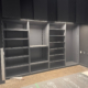Dark grey open shelving wall with upper cabinets at Deciem Labs & Studios